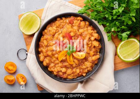 Ful Medanes oder Fava Bohnen in schwarzer Schale vor grauer Kulisse. Foul Mudammas ist ein ägyptisches, libanesisches, syrisches, eritreisches, israelisches Gericht Frühstück Stockfoto