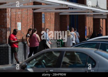 Die Käufer im Gallagher Retail Park stehen während der landesweiten Sperrung des Coronavirus vor langen Warteschlangen vor M&S und B&M. Stockfoto