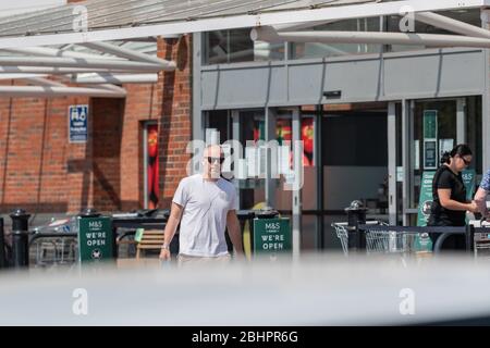 Die Käufer im Gallagher Retail Park stehen während der landesweiten Sperrung des Coronavirus vor langen Warteschlangen vor M&S und B&M. Stockfoto