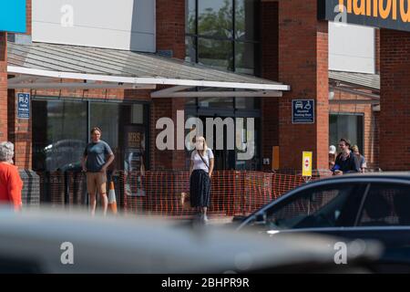 Die Käufer im Gallagher Retail Park stehen während der landesweiten Sperrung des Coronavirus vor langen Warteschlangen vor M&S und B&M. Stockfoto