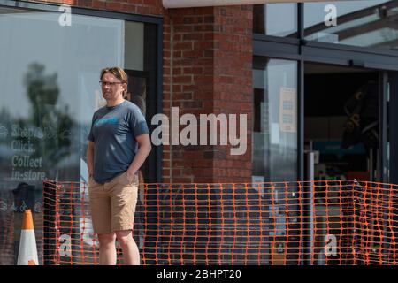 Die Käufer im Gallagher Retail Park stehen während der landesweiten Sperrung des Coronavirus vor langen Warteschlangen vor M&S und B&M. Stockfoto