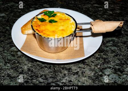 Gebratene Pilze, Huhn und Käse, der im Rahmen einer cremigen Soße in Metallschale auf einem steinernen Tisch, selektive konzentrieren. Stockfoto