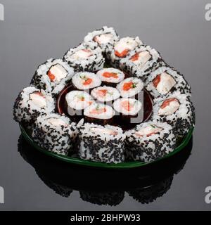 Japanisches Sushi-Essen. Maki-Brötchen und Uramaki mit Thunfisch, Lachs, Kaviar und Gurke. Die Rollen sind in Avocado-Form umrissen. Stockfoto