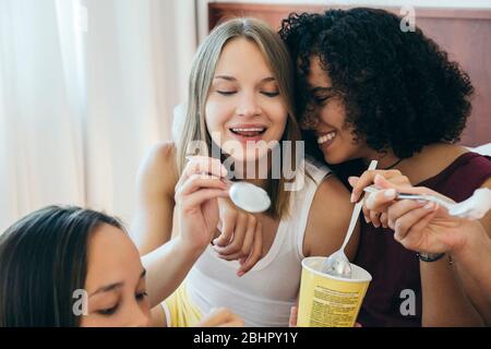 Drei Frauen essen aus Eisbecher und lachen. Stockfoto