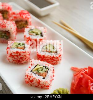 Sushi mit Essstäbchen, Ingwer, Sojasauce und Wasabi. Japanisches Essen. Sushi-Brötchen-Set mit Gemüse, Fisch und Kaviar. Japanische Speisekarte Stockfoto