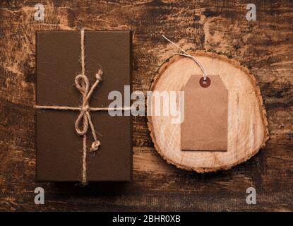 Vintage Geschenk-Box mit leeren Geschenkanhänger auf alten hölzernen Hintergrund. Stockfoto