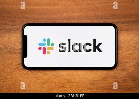 Ein Smartphone mit dem Slack-Logo liegt auf einem einfachen Holztisch (nur für redaktionelle Zwecke). Stockfoto
