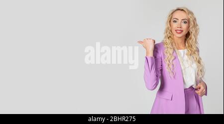 Fröhlich lächelnde Frau blonde mit blauen Augen zeigen Daumen nach links, zeigt die Richtung zeigt einen kühlen Ort, einen Freund bitten, Kaffee zu trinken, um zum Mitnehmen Lachen zu bestellen. Man sieht es besser. Stockfoto