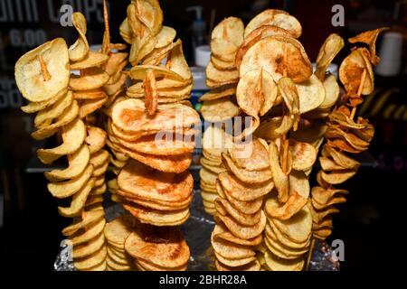 Gebratene Kartoffelspirale auf einem Stock während des Street Food Festivals. Fast Food. Tornado Kartoffeln auf einem Bambusstock Stockfoto