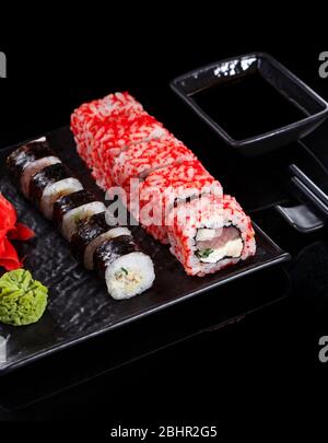 Japanisches Restaurant, Sushi-Rolle auf schwarzem Schiefer. Set für zwei Personen mit Ingwer und Wasabi auf dunklem Hintergrund. Stockfoto