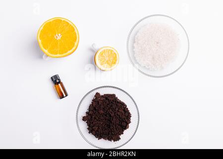Zutaten für hausgemachten Kaffee Körperpeeling mit Meersalz und Zitrusöl auf weißem Tisch, Blick von oben. Stockfoto