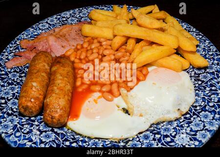 Traditionelles Englisches Frühstück mit Spiegelei, Würstchen, Bohnen, Pilze, gegrillten Tomaten und Speck auf Holz- Hintergrund. Ansicht von oben Stockfoto