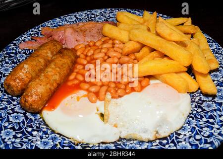 Traditionelles Englisches Frühstück mit Spiegelei, Würstchen, Bohnen, Pilze, gegrillten Tomaten und Speck auf Holz- Hintergrund. Ansicht von oben Stockfoto