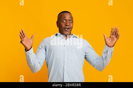 Erstaunt afroamerikanischen mittleren Alters Mann Hände heben Stockfoto