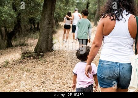 Rückansicht der Familie mit drei Kindern, die auf dem Weg durch einen Wald spazieren. Stockfoto