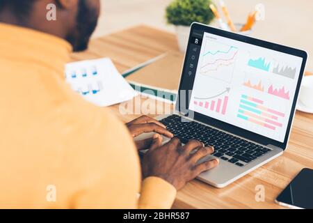 Schwarzer Unternehmer Analyse Graph auf Laptop am Arbeitsplatz Stockfoto