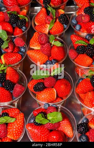 Frisch gepflückte Erdbeeren in Kunststoffglas in Italien zu verkaufen. Erdbeeren zum Verkauf, Street Food Markt. Markt für frische Lebensmittel. Stapel roter Erdbeeren Stockfoto