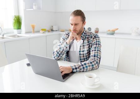 Porträt von fokussierten Geist Kerl sitzen Küche Tisch Arbeit Abstand verwenden Laptop lesen Kollegen Präsentation analysieren tragen gute aussehen Kleidung im Haus Licht Stockfoto