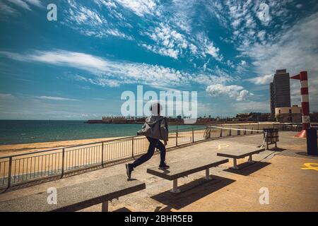 Barcelona, Spanien. April 2020. Ein Junge springt am verlassenen und abgesperrten Strand in Barcelona über Bänke am Tag, nachdem Spanien die Sperrstunde für unter 14 Jahre erleichtert hat und ihnen nach sechs Wochen einer landesweiten Sperrung aufgrund der kontinuierlichen Ausbreitung einen einstündigen begleiteten Spaziergang durch die nahe Nachbarschaft gewährt Des Corona-Virus. Spanien verzeichnete bis jetzt rund 300 neue Todesfälle mit einer Todesrate von fast 23500 Todesfällen. Quelle: Matthias Oesterle/Alamy Live News Stockfoto