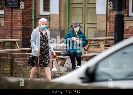 Sheffield UK – März 30 2020: Ältere Frau in PSA-Maske geht während der Coronavirus Covid-19-Pandemie in der Richmond Road an einem älteren maskierten Mann vorbei Stockfoto