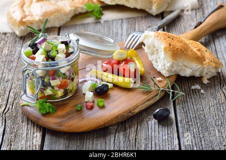 Griechischer Bauernsalat mit Feta-Käse und schwarzen Oliven in einem Glasgefäß, serviert mit dem typischen Pita-Brot Stockfoto