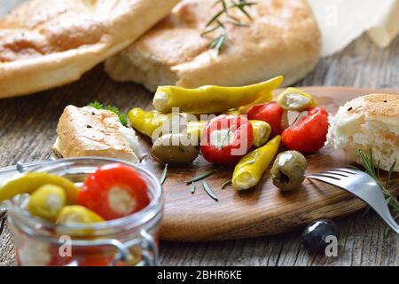 Griechischer Snack: Kirschpaprika und Chili gefüllt mit Frischkäse, serviert mit Oliven und frischem Pita-Brot Stockfoto