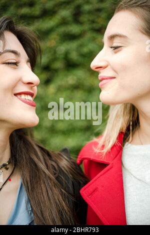 Kopf und Schultern von zwei Frauen im Profil, die einander angucken und lächeln. Stockfoto