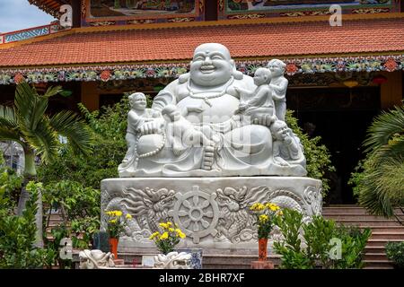Marmorskulptur des glücklichen Buddha mit Kindern in einem buddhistischen Tempel in der Stadt Danang, Vietnam. Nahaufnahme Stockfoto