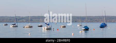 Zahlreiche Segelboote ankern am Ammersee. Einige Boote sind mit Plane bedeckt. Segeln ist eine beliebte Freizeitbeschäftigung in oberbayern. Stockfoto