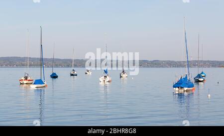 Segelboote ankern in einer Bucht bei Herrsching am Ammersee. Die Segelsaison beginnt zwischen März und Mai. 16:9-Panoramafotorformat. Stockfoto