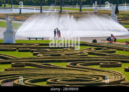 Hannover, Deutschland. April 2020. Zwischen Blumenbeeten und Springbrunnen schlendern Besucher durch die Herrenhäuser Gärten. Die Herrenhäuser Gärten mussten wegen der Corona Pandemie für mehrere Wochen geschlossen werden. Kredit: Ole Spata/dpa/Alamy Live News Stockfoto