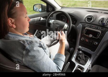 Fahrerfrau, die den Sicherheitsgurt vor ihrem fahrsicheren Fahrkonzept anschnürt Stockfoto