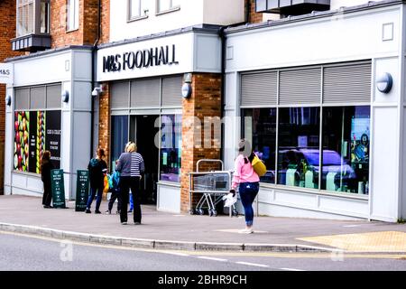 Einkäufer, die vor EINER Marks and Spencer Food Hall in South London Schlange stehen und die Richtlinien zur Lockdown-Richtlinie der Regierung zur sozialen Distanzierung einhalten Stockfoto