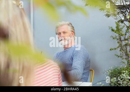 Nahaufnahme eines Paares, das sich gegenüber an einem Tisch in einem Garten sitzt. Stockfoto