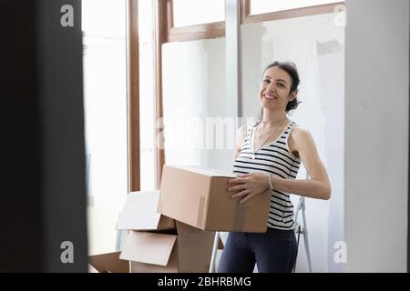 Eine Frau lächelt und trägt einen Karton. Stockfoto