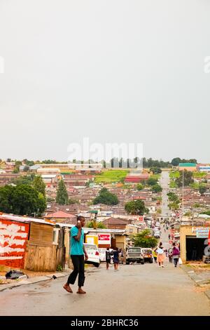 Johannesburg, Südafrika - 17. Januar 2011: Afrikaner gehen eine Hauptstraße in Alexandra Township entlang, eine formelle und informelle Siedlung Stockfoto