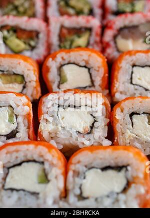 Sushi-Brötchen mit japanischer Küche im Restaurant. Sushi-Brötchen mit Lachs, Gemüse und Kaviar-Nahaufnahme. Japanische Speisekarte Stockfoto