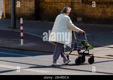 Eine alte Dame mit einem Geher überquert eine Straße, Alte Frau mit Rollator Stockfoto