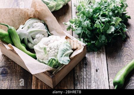 Frische Bio-Hausblumen und Koriander Kräuter auf rustikalem Holztisch, nachhaltiges Leben, gesunde Ernährung, pflanzliche Lebensmittel, Kochzutat Stockfoto