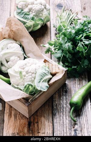 Frische Bio-Hausblumen und Koriander Kräuter auf rustikalem Holztisch, nachhaltiges Leben, gesunde Ernährung, pflanzliche Lebensmittel, Kochzutat Stockfoto