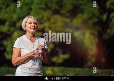Reife Frau, die Wasser nach dem Joggen trinkt Stockfoto