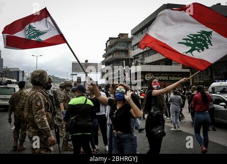 Zouk Mikael, Libanon. April 2020. Regierungsfeindliche Demonstranten schwenken libanesische Flaggen während eines Protestes gegen die hohen Lebenshaltungskosten und die Abwertung der lokalen Währung in Zouk Mikael. Dutzende Demonstranten versammelten sich und blockierten am Montag wichtige Straßen, um gegen die sich verschlechternde Wirtschaftskrise des Landes zu protestieren und sich einer Sperrung des Coronavirus zu widersetzen. Quelle: Marwan Naamani/dpa/Alamy Live News Stockfoto