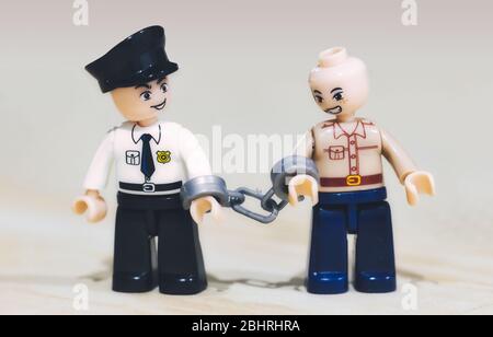 Spielzeug-Miniaturfiguren: Ein Krimineller wird von einem Polizisten verhaftet Stockfoto