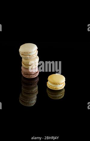Bunte Macarons mit Spiegelung isoliert auf schwarzem Hintergrund. Süßer französischer Kuchen. Stockfoto