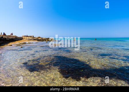 Wunderschönes kristallklares Wasser. Isola delle Correnti (Insel der Strömungen), Portopalo di Capo Passero, Syrakus, Sizilien. Leute, die am Strand baden. Stockfoto