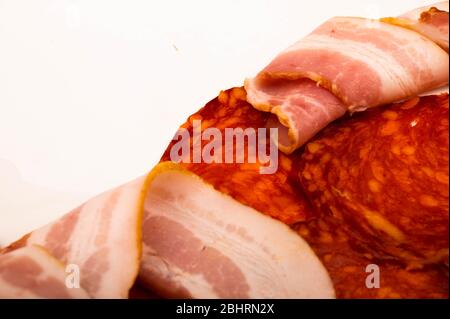 Scheiben Wurst und Speck auf weißem Hintergrund. Nahaufnahme Stockfoto