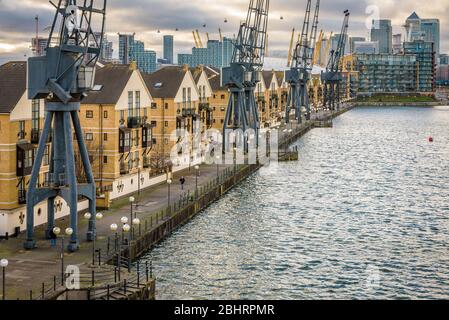 London, England. Britannia Village und seine Kraniche von der Royal Victoria Dock Bridge aus gesehen, mit den Canary Wharf Wolkenkratzern im Hintergrund. Stockfoto
