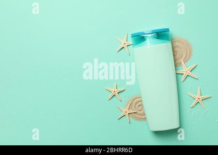 Flasche Shampoo, Seesterne und Sand auf Minzgrund Stockfoto