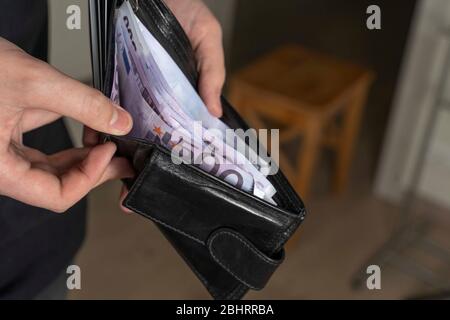 Ein Mann mit einer schwarzen Brieftasche voller europäischer Währung oder europäisches Geld. In einer schwarzen Geldbörse Banknote für 500 Euro. Erhöhung der Gehälter und Renten, werden Stockfoto