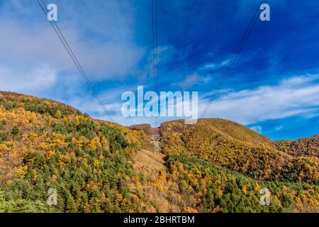 Hochspannungsleitung in der Mitte eines schönen farbigen Waldes. (Herbst) Stockfoto